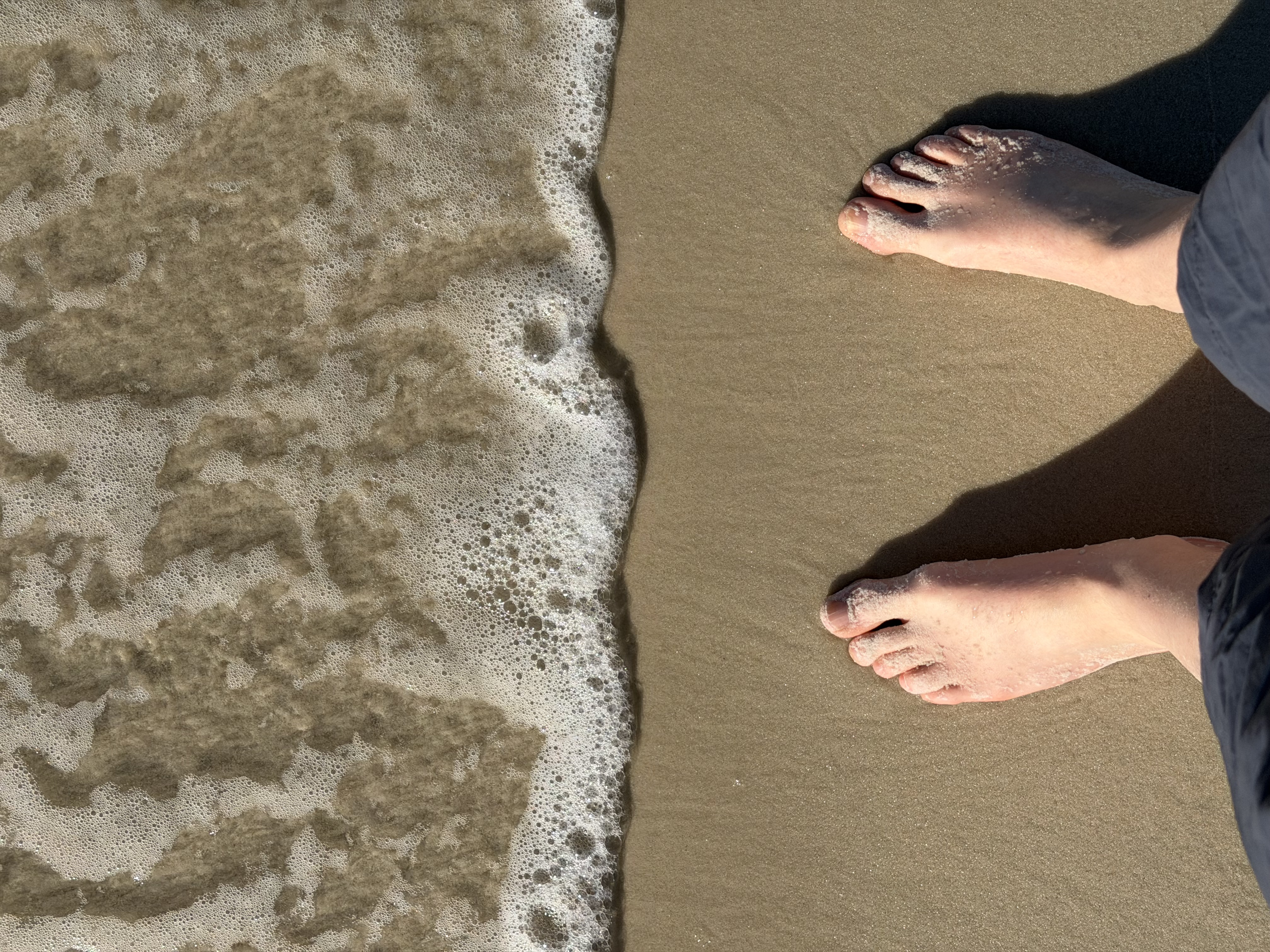 My feet on the beach with the water coming in. 